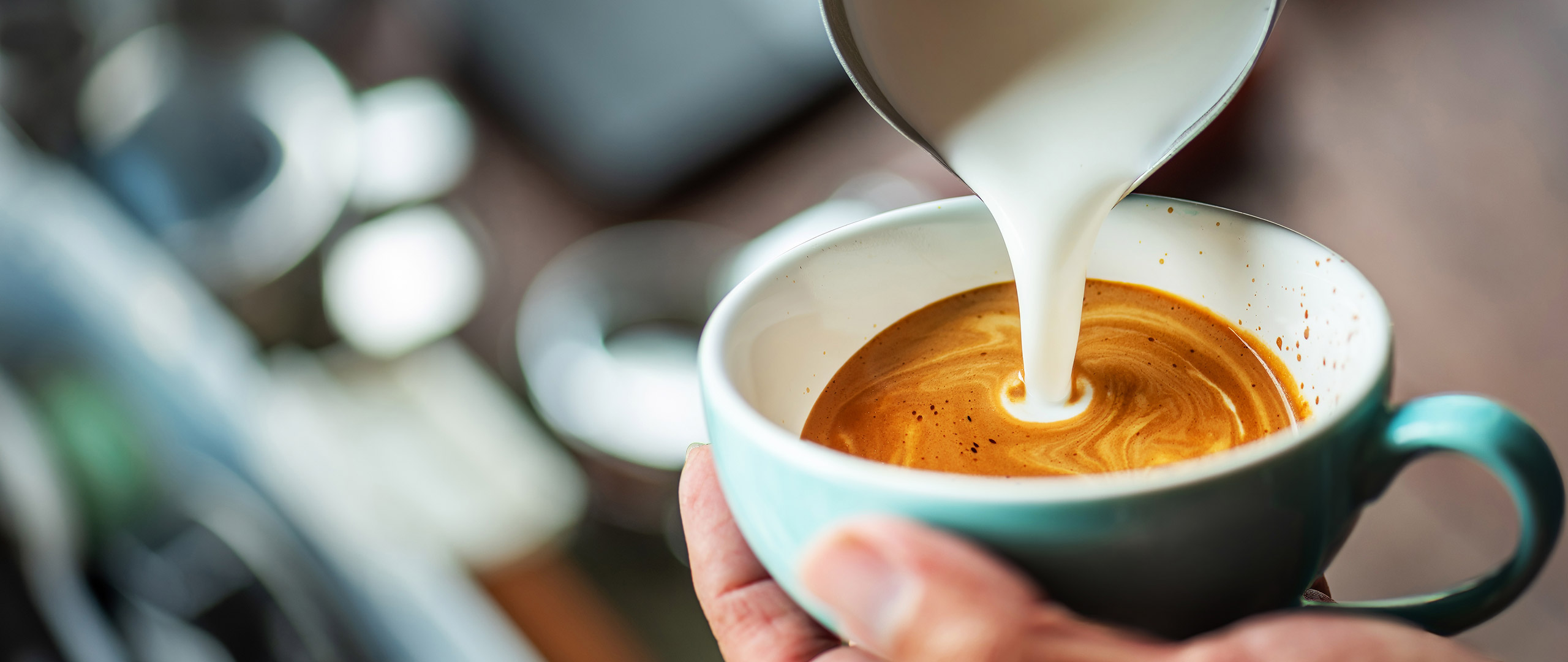 Pouring milk into a cup of coffee